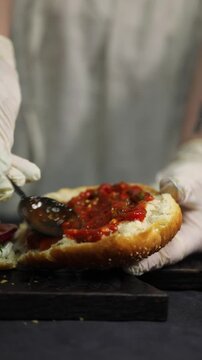 A woman prepares homemade burgers in a kitchen, cooking and assembling fresh ingredients in a process that reflects both home kitchen and professional restaurant-style cooking.