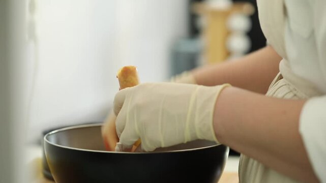 A woman prepares cannelloni by stuffing pasta tubes with minced meat in a kitchen, showing a detailed cooking process suitable for both home-style meals and professional restaurant cuisine.