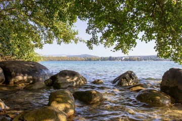 Obraz premium Shaded rocks and leafy shore on Lake Annecy