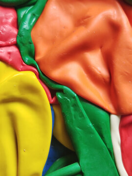 Primer plano de globos de l&aacute;tex desinflados con texturas rugosas y pliegues en colores naranja, amarillo, verde y rosa