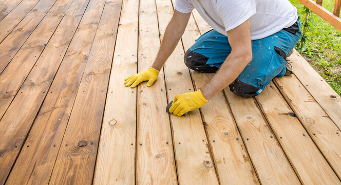 Worker crouches on wooden deck
