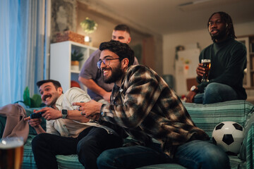 Friends playing competitive video game soccer at home, enjoying beer and shared male bonding experience © Zamrznuti tonovi