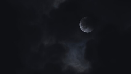 Obraz premium Mysterious moon shining through dark ominous clouds in the night sky