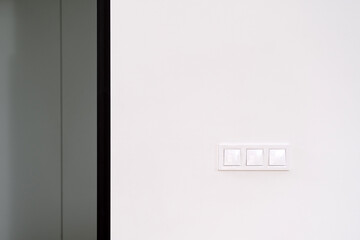Modern white light switch panel on clean wall in residential apartment