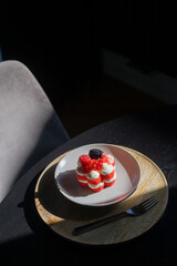 Minimalist red velvet berry cake on white plate and wooden tray