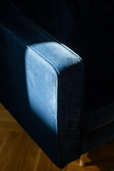 Closeup of blue velvet sofa armrest in minimalist living room