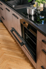 Modern kitchen with open oven, induction hob and wooden floor