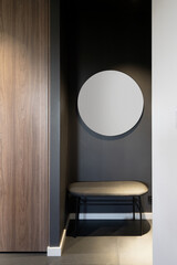 Modern minimalist apartment entryway with round mirror and bench