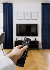 Man with remote control choose program on tv