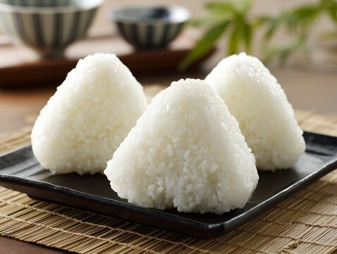 黒い皿の上に並べられたふっくらと美味しそうに握られた三角形の白い塩むすびの三個セット