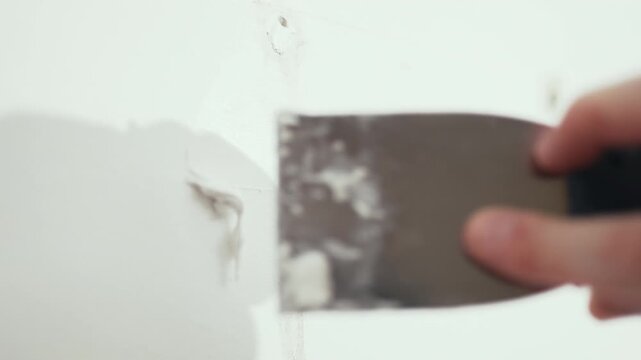Handyman filling holes on white wall with putty knife, wall preparation process, high quality 10 bit 4K.