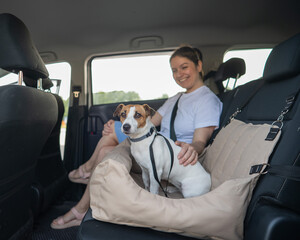 Caucasian woman travels by car with her dog. Jack Russell Terrier in a special car seat.  © Михаил Решетников