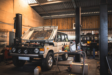 Classic off-road vehicle undergoing maintenance in a workshop with tools and fluids © Pavel Babic