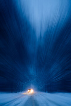 Front view of a car with headlights on driving along a snowy road at dusk, Cook County, Illinois, USA
