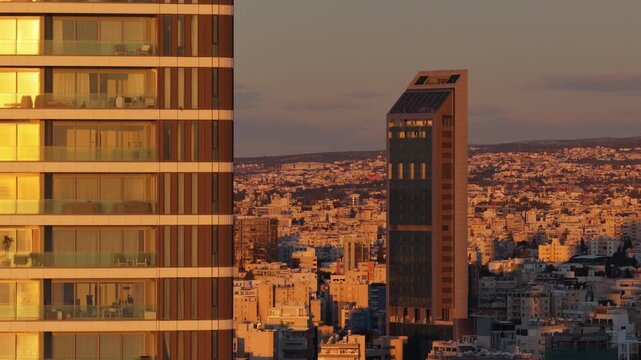 Aerial drone view of modern building facade reflecting warm sunset light in Limassol, Cyprus
