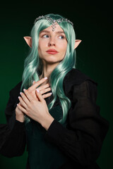 Obraz premium Beautiful girl dressed as elf on dark green background