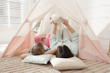 Mother and her daughter with toy near wigwam at home © New Africa