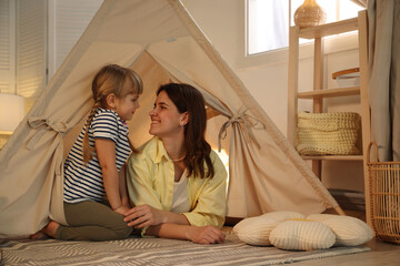 Mother and her daughter in toy wigwam at home © New Africa