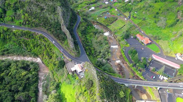 An aerial view captures Madeira's lush green valleys and the dramatic, winding roads that carve through its mountainous landscape. A scenic journey through nature. Faial