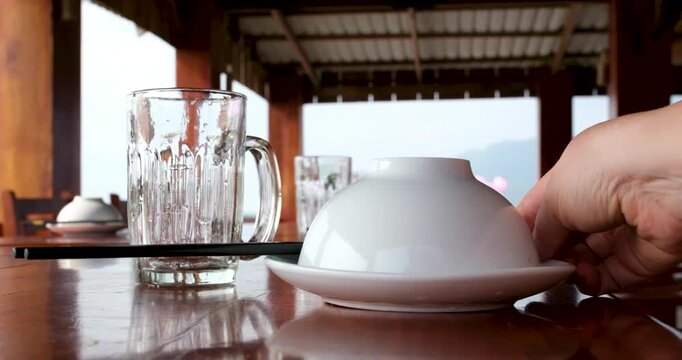 Table setup for hot pot on wooden table with upside-down bowls, Vietnamese spoons and empty glasses outdoors over water on Phu Quoc island Vietnam