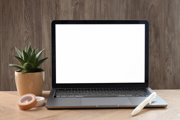 Fototapeta premium Stylish workplace with laptop, stationery and floral decor on wooden table