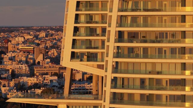 Aerial drone view of modern building facade reflecting warm sunset light in Limassol, Cyprus