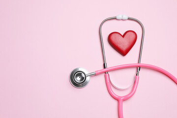Stethoscope and heart figure on pink background, flat lay © New Africa