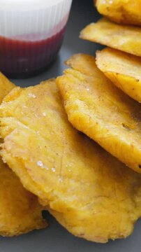 Fried platanos on plate. Sliced and cooked tostones. Rotating. Vertical footage
