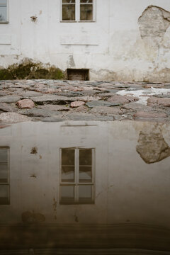 Old building reflecting in street puddle