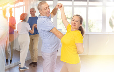 Fototapeta premium Elderly man and elderly woman dance ballroom dance waltz in studio