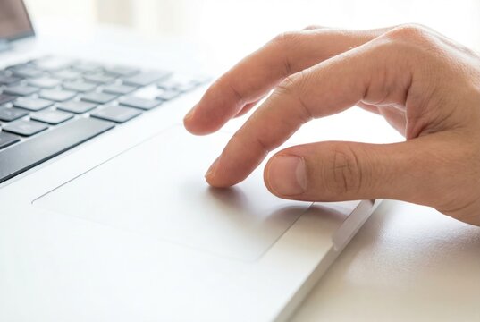 Close up of a hand using a laptop trackpad on a white desk