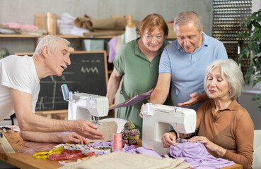 Obraz premium During educational lesson on cutting and sewing, elderly students listen to senior female teacher, watch demonstration, and gain skills in hand-made clothing..