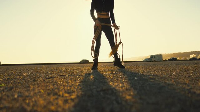 Silhouette of a woman untying a rope during golden hour