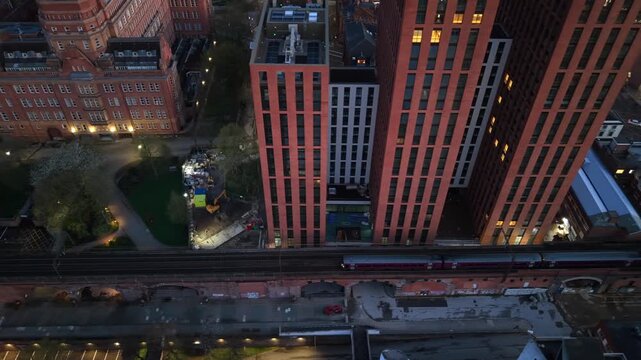 Aerial video featuring a passenger train travelling over a viaduct in Manchester toward Oxford Road station. 