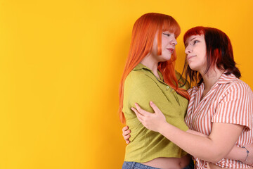 Lovely lesbian couple on yellow background, space for text. LGBT concept