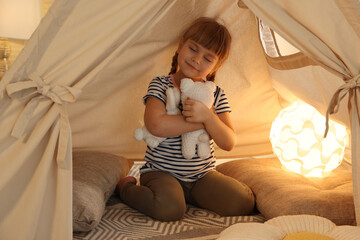 Little girl playing with toys in wigwam at home © New Africa