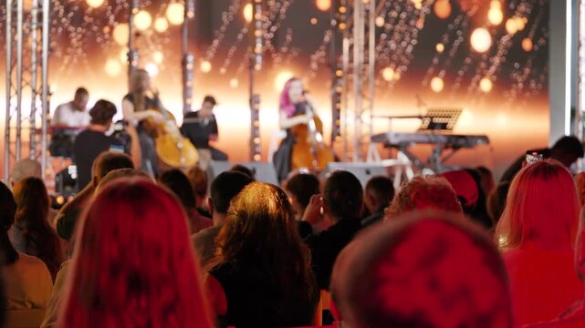 Attentive audience watching a live music concert with cellists on stage
