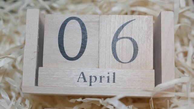 Perpetual wooden calendar set to April 6 with clear typography and shallow depth of field. Clean framing emphasizes simple timekeeping concept.