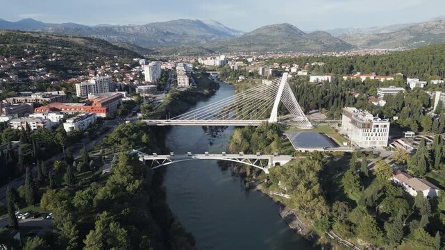 Aerial forward flight over Moraca river with modern bridges and Podgorica city panorama, Montenegro.