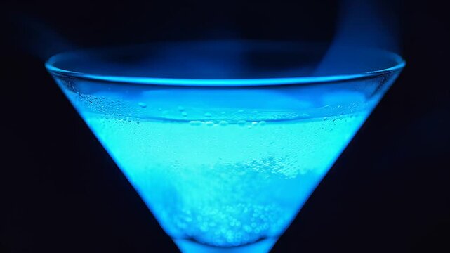Closeup of a vibrant blue cocktail being prepared with ice and bubbles.