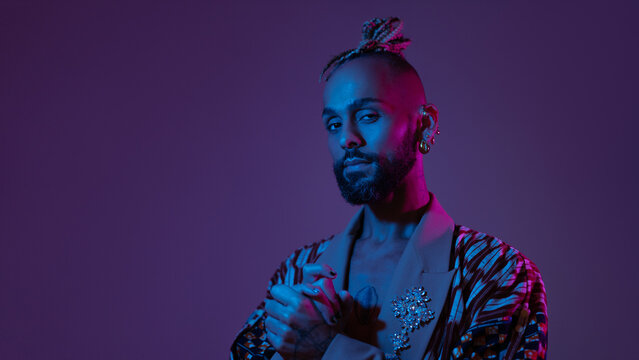 Neon light studio close-up portrait handsome black gay man looking camera. Seductive sexy man wear make up, transgender person in ultraviolet light. Nightclub and nightlife concept