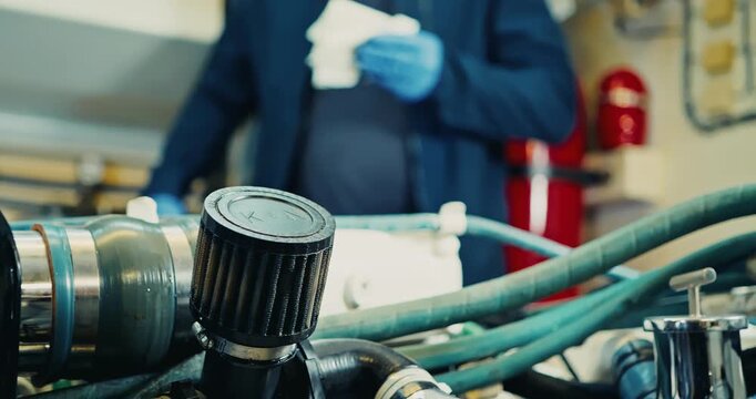 Technician Inspecting Engine Room with Hoses and Valves