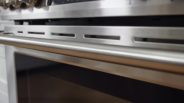 Closeup of a modern stainless steel oven door handle and control panel.