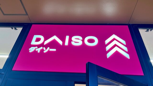 DAISO store signage with glowing LED letters and three-arrow logo on a vibrant pink background at a modern Japanese retail shopping mall entrance - Tokyo, Japan, May 15, 2024