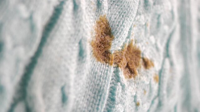 Macro view of brown chocolate stain on blue knitted sweater fabric with detailed textures.