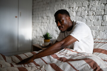Fototapeta premium Man waking up stretching in bed in bedroom