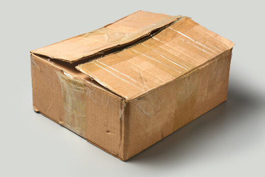 used old closed brown cardboard box isolated grey background, shipping carton with clear adhesive tape, angle view