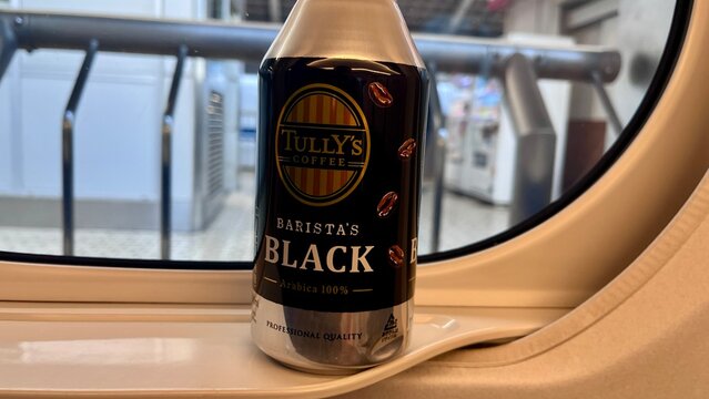 Tully's Coffee Barista's Black ready-to-drink aluminum bottle resting on a Shinkansen bullet train window ledge during travel through Tokyo - Tokyo, Japan, October 15, 2024