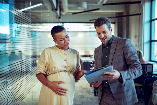 Coworkers discussing project on tablet in modern office