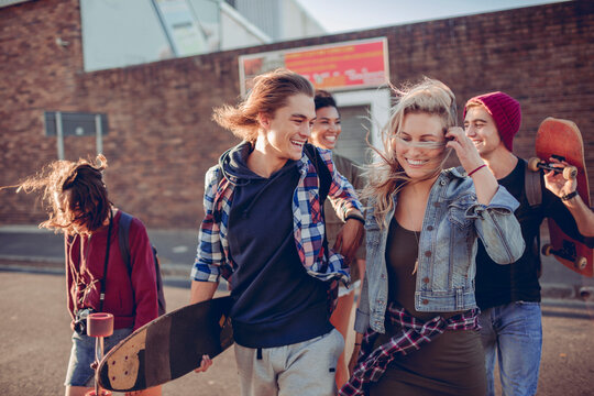 Group of friends with skateboards walking on city street